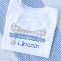 Canoe Zigzag Applique Embroidery Design: Tan gingham canoe with a paddle over blue waves above the name Lincoln stitched on a white shirt