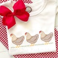 Chicken Trio Sketch Stitch Embroidery Design: Three tan sketch stitch hens in a row on grass stitched on a white shirt with a red bow