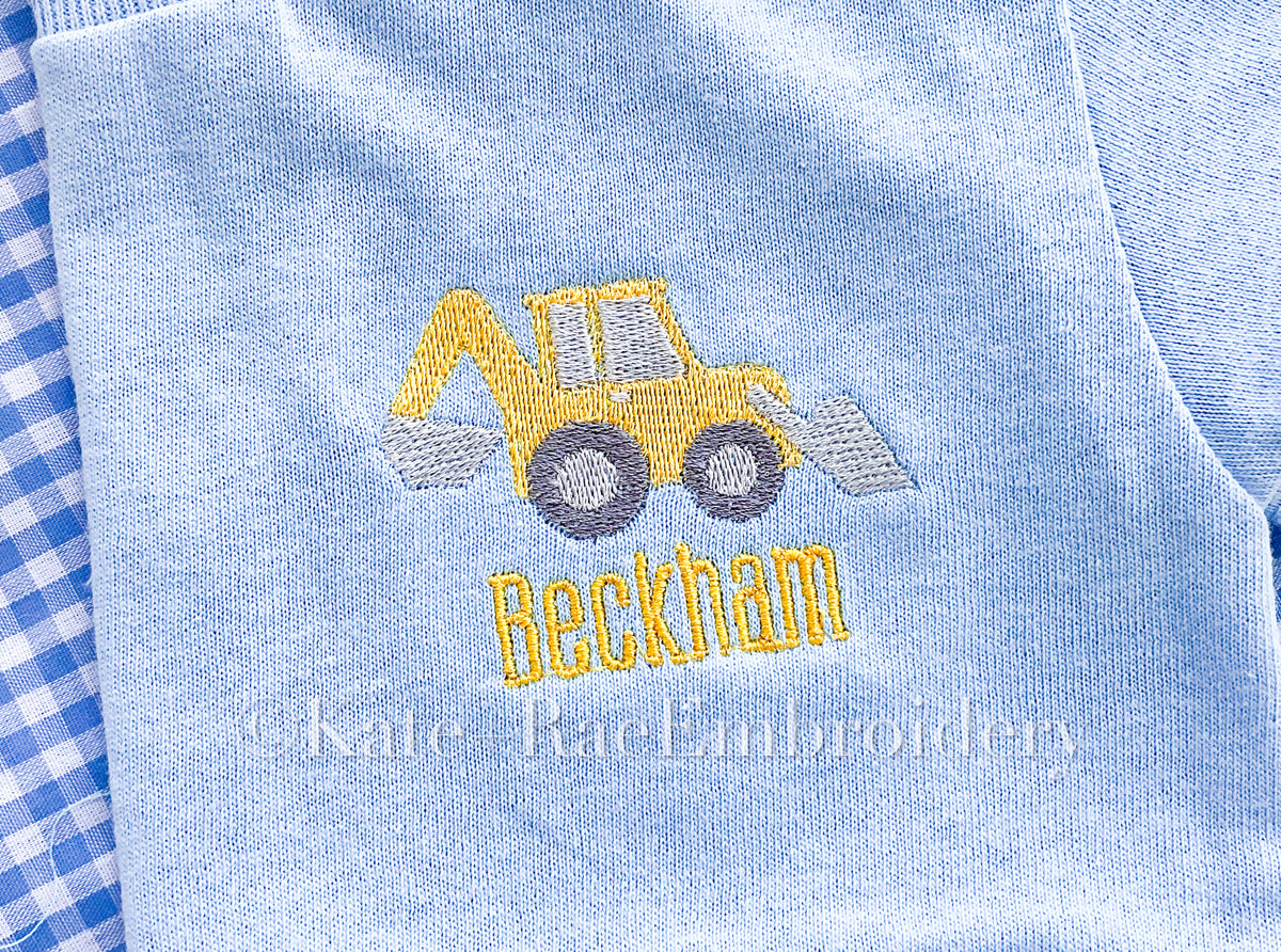Backhoe Mini Fill Embroidery Design: Small yellow backhoe above the name Beckham stitched on a light blue shirt