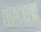 Simple Life Zigzag Stitch Applique Embroidery Font: Close-up of the name Jack in mint zigzag applique letters on blue seersucker