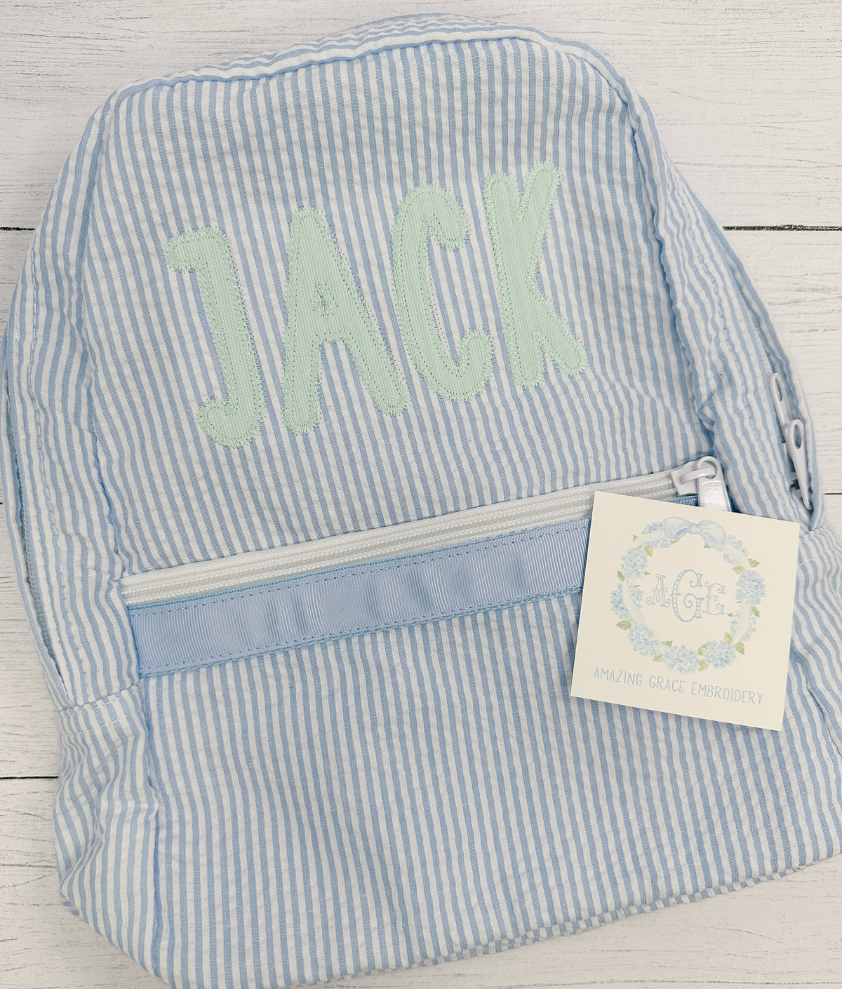 Simple Life Zigzag Stitch Applique Embroidery Font: The name Jack in mint applique letters on a blue seersucker backpack