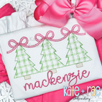 Girls Plaid Christmas Tree Trio with Connecting Bows Sketch Stitch Embroidery Design: Three green plaid Christmas trees linked by pink bows above the name mackenzie in pink script on a white shirt