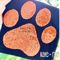 Paw Print Zigzag Stitch Applique Embroidery Design: Orange sequin paw print applique on a navy shirt