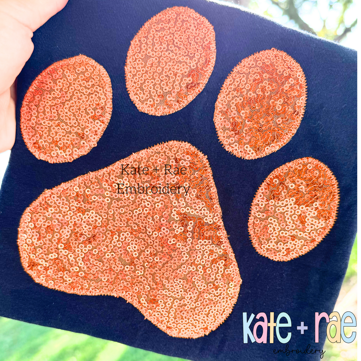 Paw Print Zigzag Stitch Applique Embroidery Design: Orange sequin paw print applique on a navy shirt