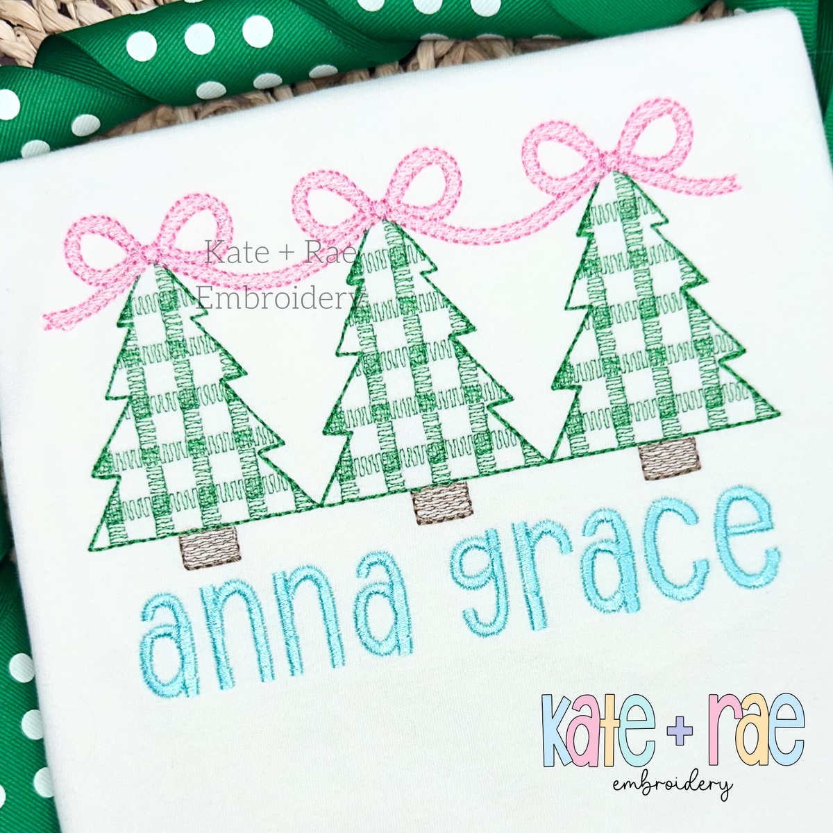 Girls Plaid Christmas Tree Trio with Connecting Bows Sketch Stitch Embroidery Design: Three green plaid Christmas trees linked by pink bows above the name anna grace in aqua on a white shirt