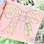 Kinley Bow Zigzag Stitch Applique Embroidery Design: Large pink floral bow applique with the name kinley on the tail on a pink shirt
