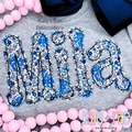 Dottie Bean Stitch Applique Embroidery Font: The name Mila in blue floral bean stitch applique letters on a gray sweatshirt