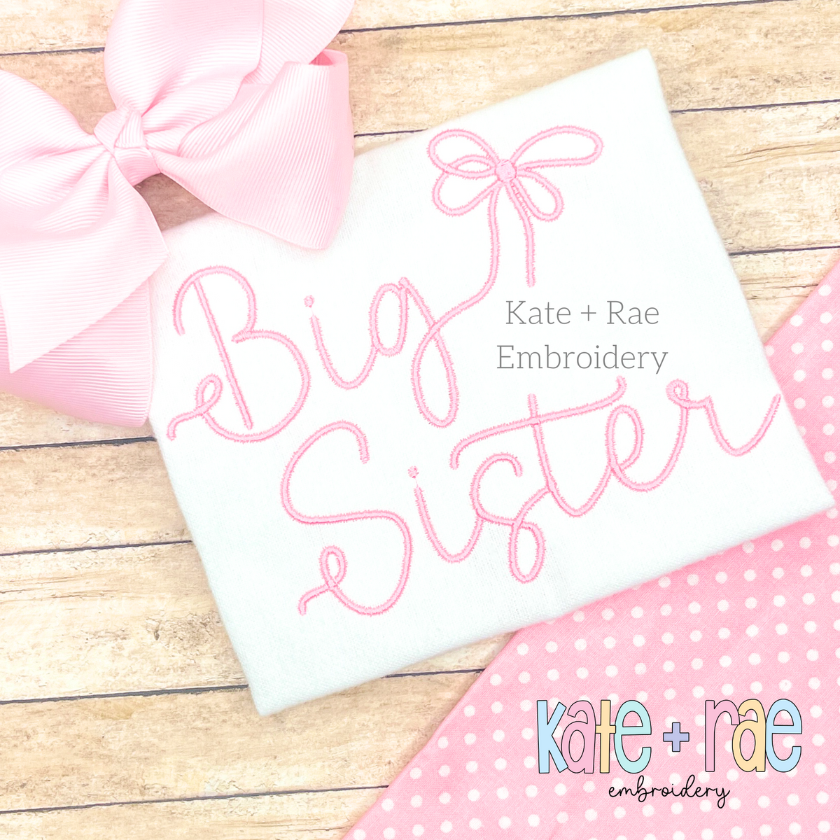 Preppy Big Sister Embroidery Design: The words Big Sister in pink script with a bow on a white shirt