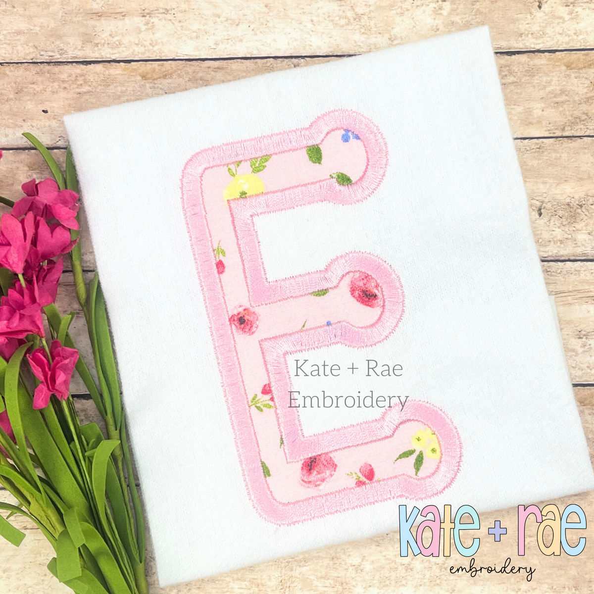 Dottie Satin Stitch Applique Embroidery Font: Pink floral applique letter E on a white shirt