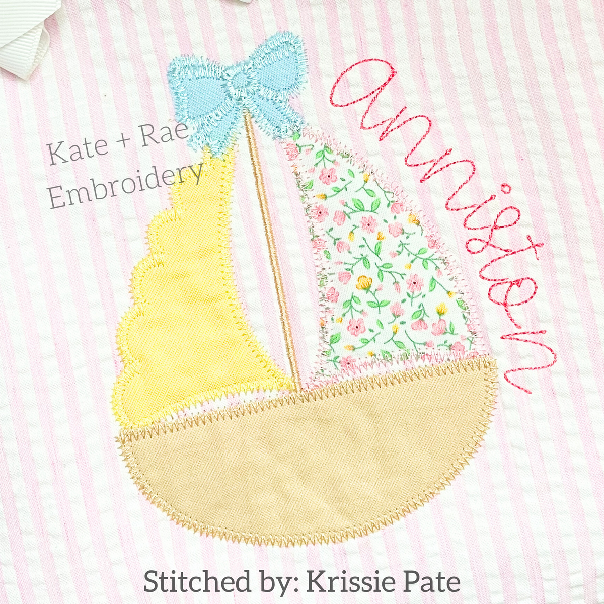 Girl's Scalloped Sailboat Zigzag Applique Embroidery Design: Scalloped sailboat with a blue bow and yellow and floral sails beside the name Anniston on pink seersucker