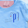 Fishing Pole Mini Fill Embroidery Design: Small fishing pole with a red and white bobber beside a blue letter P on a light blue shirt