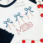 Girl's Baseball Trio with Bows Sketch Stitch Embroidery Design: Three sketch stitch baseballs with blue bows above the name Millie in red on a white shirt