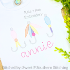 Fishing Lure Trio Sketch Stitch Embroidery Design: Three pastel sketch stitch fishing lures above the name annie in pink script on a white shirt