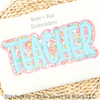 Teacher Double Satin Stitch Applique Embroidery Design: The word TEACHER in aqua letters with a pink floral outline on a cream sweatshirt