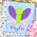Butterfly Zigzag Stitch Applique Embroidery Design: Butterfly applique with purple wings and a green body above the name Kaylee in purple script on a blue shirt