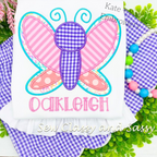 Butterfly Satin Stitch Applique Embroidery Design: Butterfly applique with pink striped and polka dot wings above the name Oakleigh in pink on a white shirt
