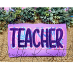 Teacher Double Satin Stitch Applique Embroidery Design: The word TEACHER in purple glitter letters with a pink and blue swirl outline on a purple sweatshirt