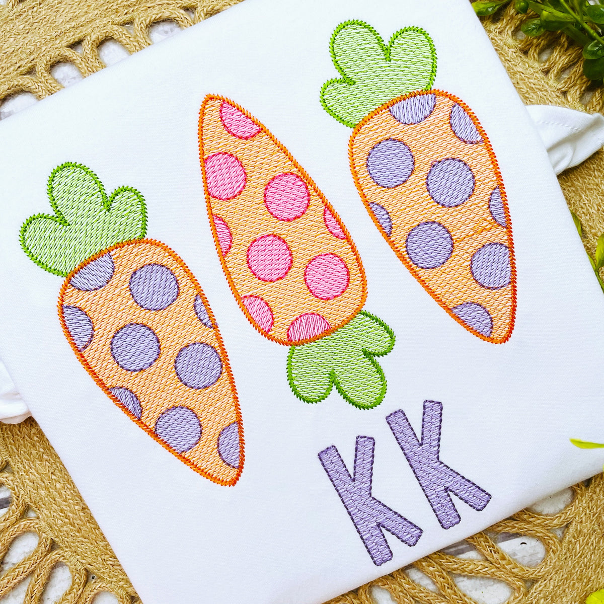 Cupcake Sketch Stitch Embroidery Font: Three polka dot sketch stitch carrots above the letters KK in purple on a white shirt
