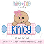 Gingerbread Girl with Rolling Pin Name Plate Zigzag Applique Embroidery Design: Design preview of a gingerbread girl with a pink bow holding a pink gingham candy name plate reading Kinley, available in 5x7, 6x10, 7x12, and 8x8